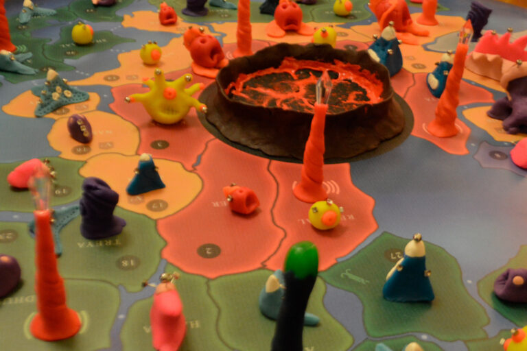 Regiões centrais do tabuleiro do jogo Planeta Insano na Ludos Luderia após o prelúdio, com espécies espalhadas pelo mapa, altares da transmutação ativos e o núcleo do planeta em ebulição cercado por criaturas.