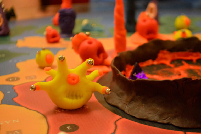 Criatura amarela do jogo Planeta Insano próxima ao núcleo vulcânico do planeta, com outras espécies ao fundo e altar da transmutação ativo, simbolizando adaptação e ameaça iminente.