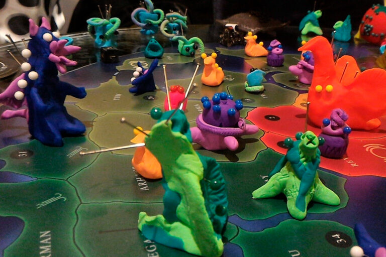 Criaturas coloridas do jogo de tabuleiro Planeta Insano ocupando territórios durante uma Terça Nerd