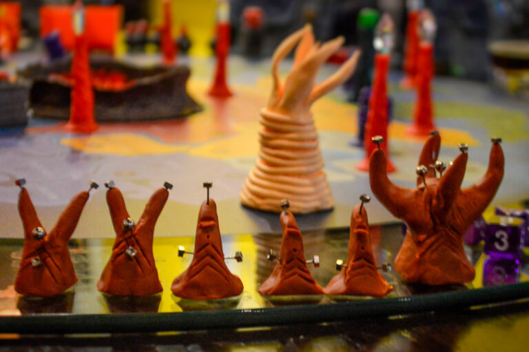 Criatura ancestral do deserto no jogo de tabuleiro Planeta Insano cercada por espécies menores durante uma Terça Nerd