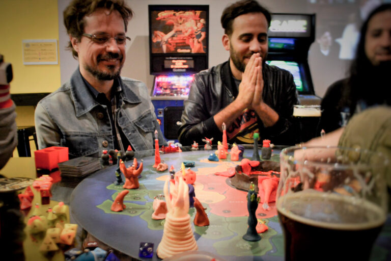 Jogadores observando o tabuleiro do Planeta Insano durante uma partida em Terça Nerd