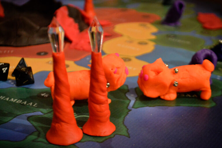 Criaturas laranjas feitas de massinha ocupam uma região do tabuleiro do jogo Planeta Insano